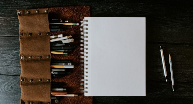 Blank Bid Document A blank notepad ready for bid writing brainstorming with pens and pencils on a brown leather holder.