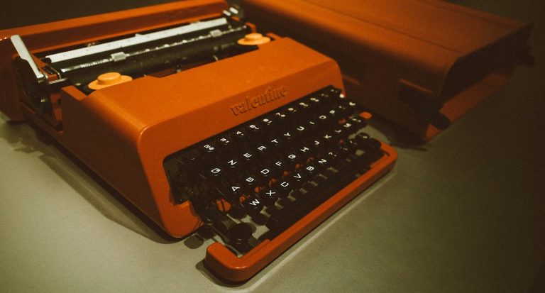 Orange Typewriter Retro orange typewriter on a dark surface, ready to type a bid document, angled view showing keys and carriage.